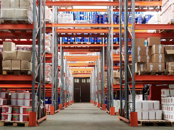 Wide angle view of a warehouse with stocked shelves and boxes.
