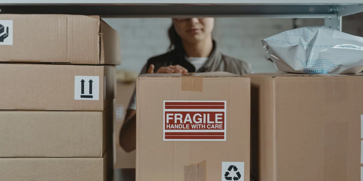 A person organizing fragile cardboard boxes in a warehouse setting.