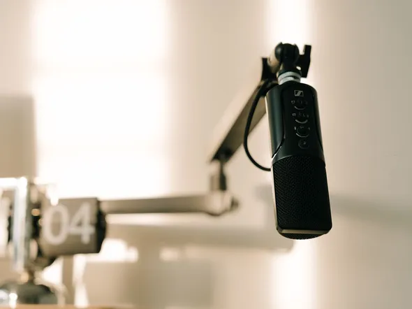 A sleek professional microphone on a boom arm in a minimalist studio.