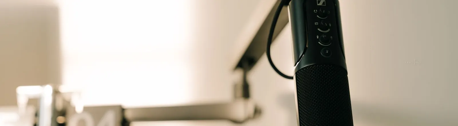 A sleek professional microphone on a boom arm in a minimalist studio.