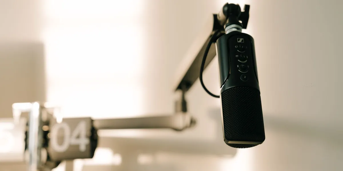 A sleek professional microphone on a boom arm in a minimalist studio.