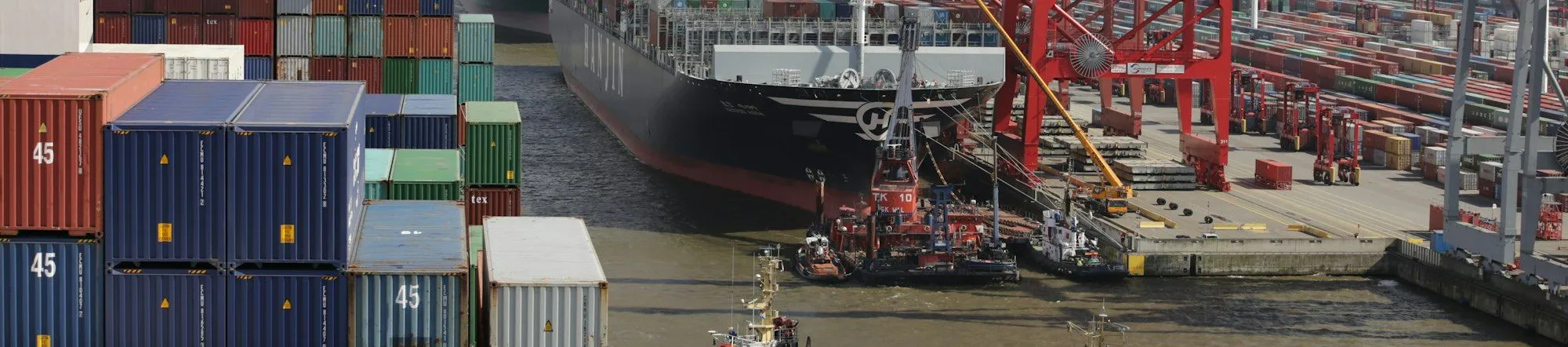 Tug boat assisting a large cargo ship into a freight port