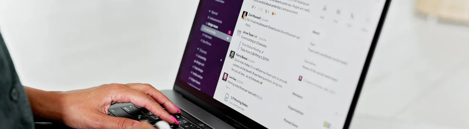 A woman types on a laptop using a messaging app in a modern office setting.