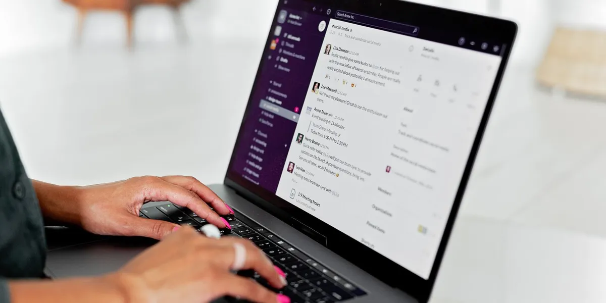 A woman types on a laptop using a messaging app in a modern office setting.