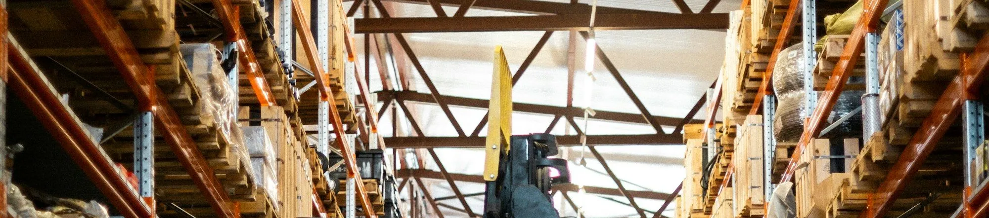 Yellow forklift operating inside a large logistics warehouse