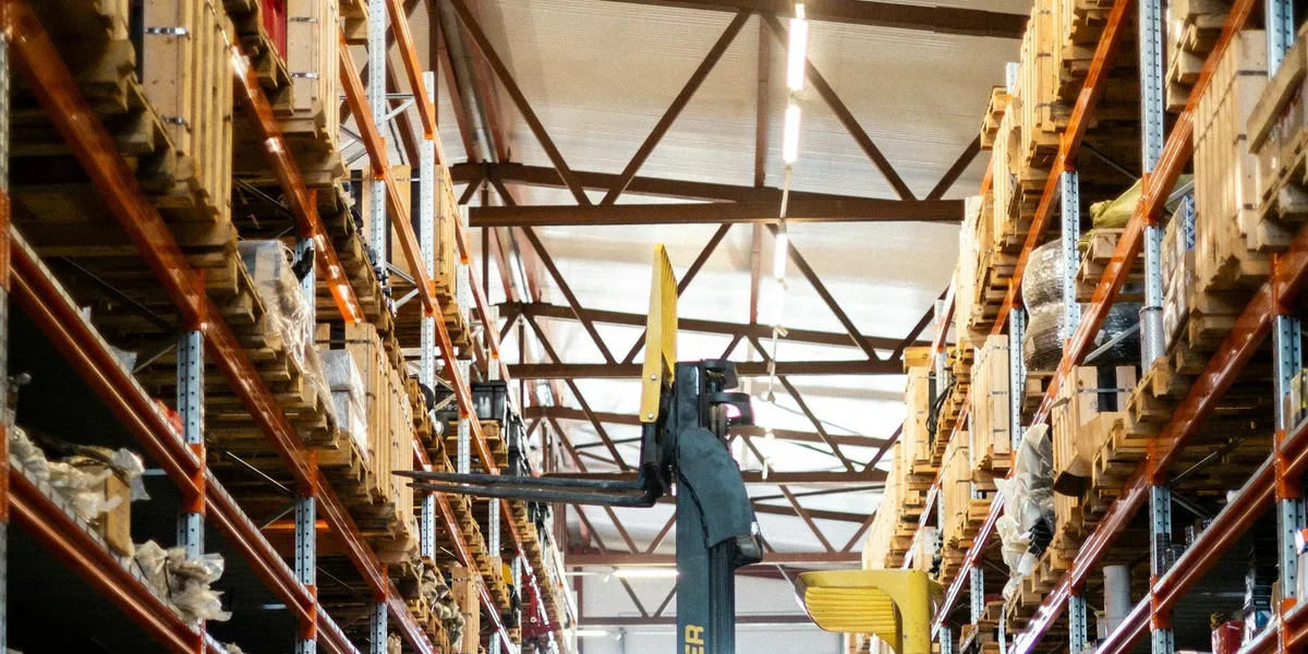 Yellow forklift operating inside a large logistics warehouse