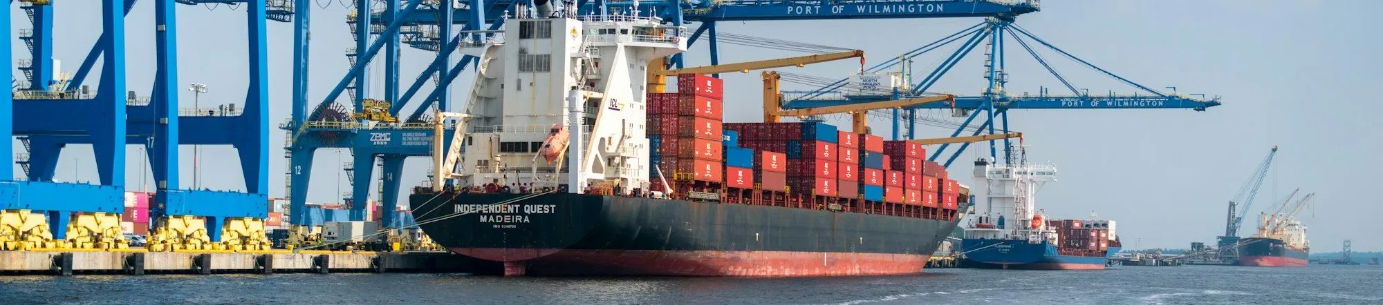 Cargo ship docked at a port with industrial cranes in the background