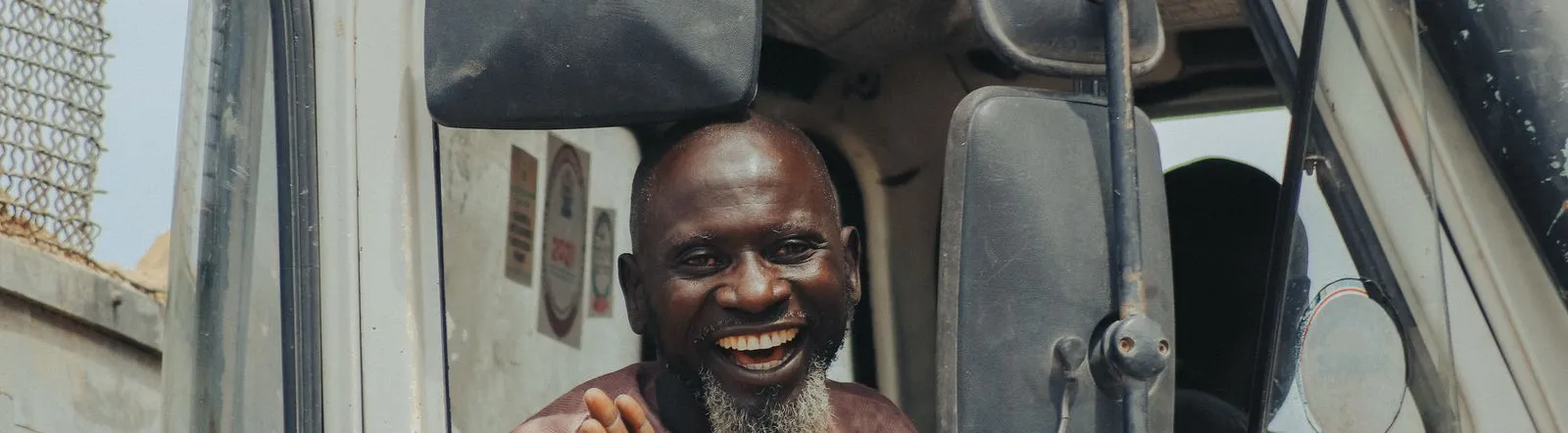 Cheerful truck driver waving and smiling from his vehicle's window.