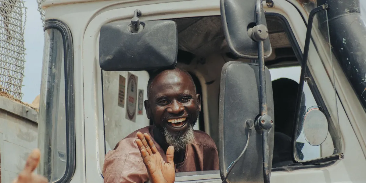 Cheerful truck driver waving and smiling from his vehicle's window.