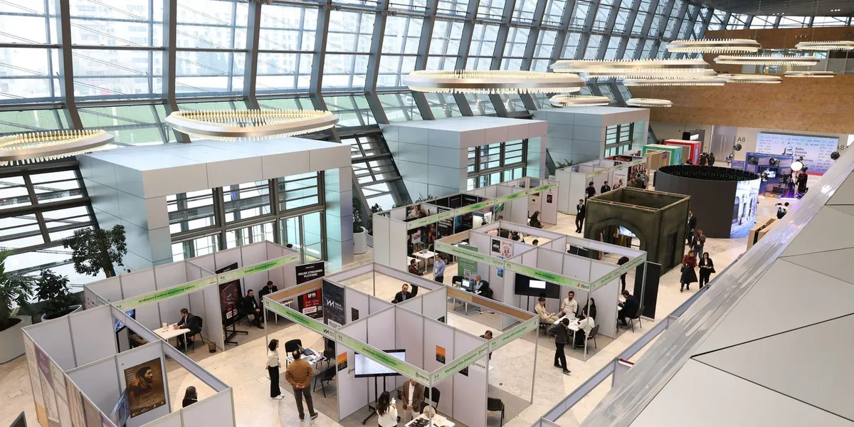 A bustling trade show exhibition inside a modern hall with people networking and exploring booths.