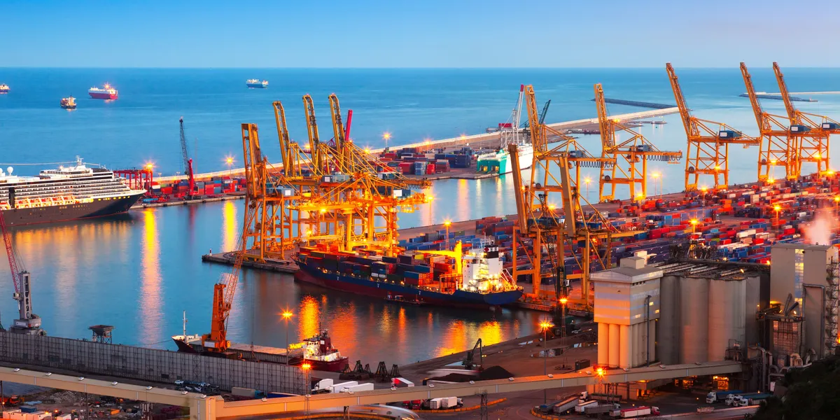 Port of Barcelona at dusk with gantry cranes and cargo vessels under warm light