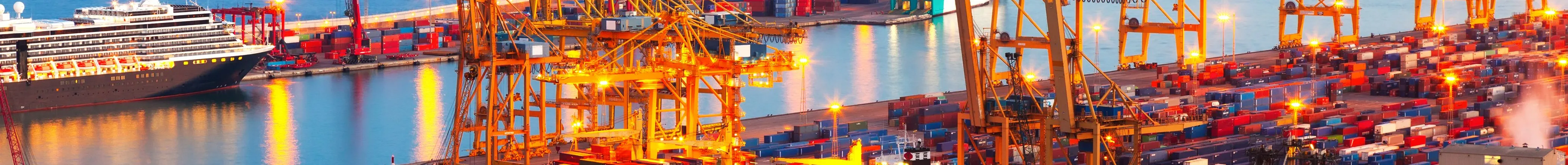 Port of Barcelona at dusk with gantry cranes and cargo vessels under warm light