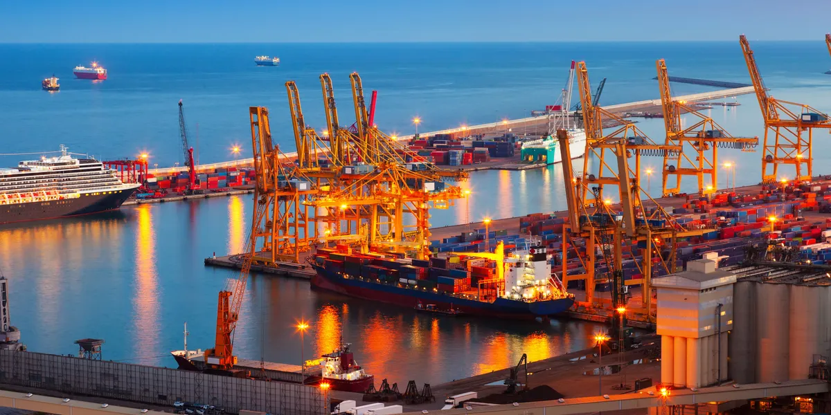 Night view of an active commercial port with lit cranes and docked cargo ships