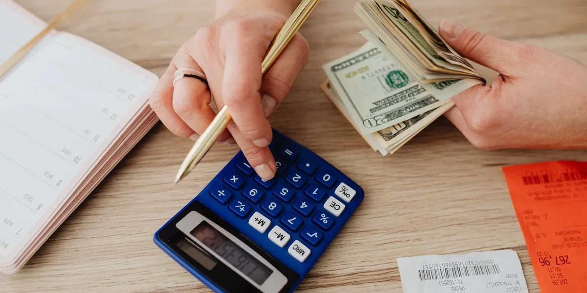 Hands handling cash and calculator for budget planning. Modern financial scene.