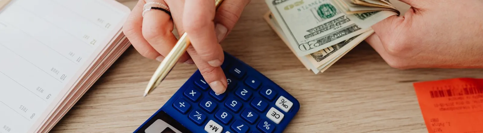 Hands handling cash and calculator for budget planning. Modern financial scene.