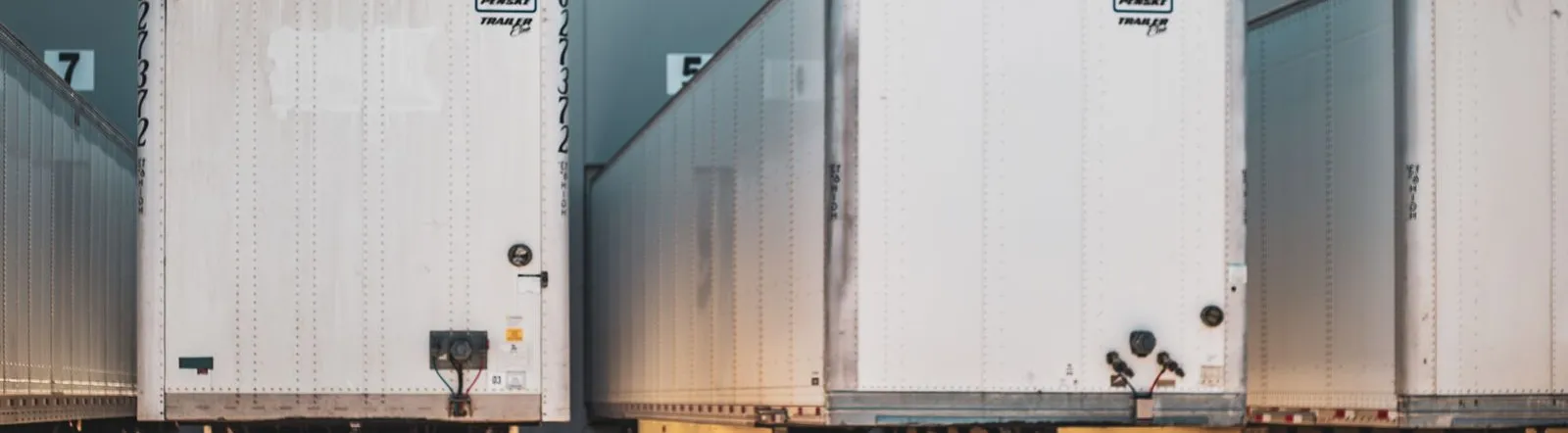 A row of freight trailers parked at a commercial loading dock, emphasizing transportation and logistics.