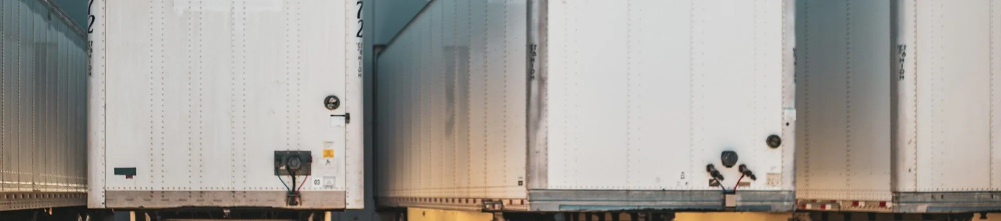 Multiple semi trucks parked next to each other at a freight depot