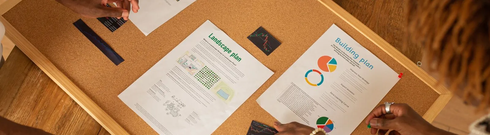 A diverse team collaborates on a workspace board with charts and plans.