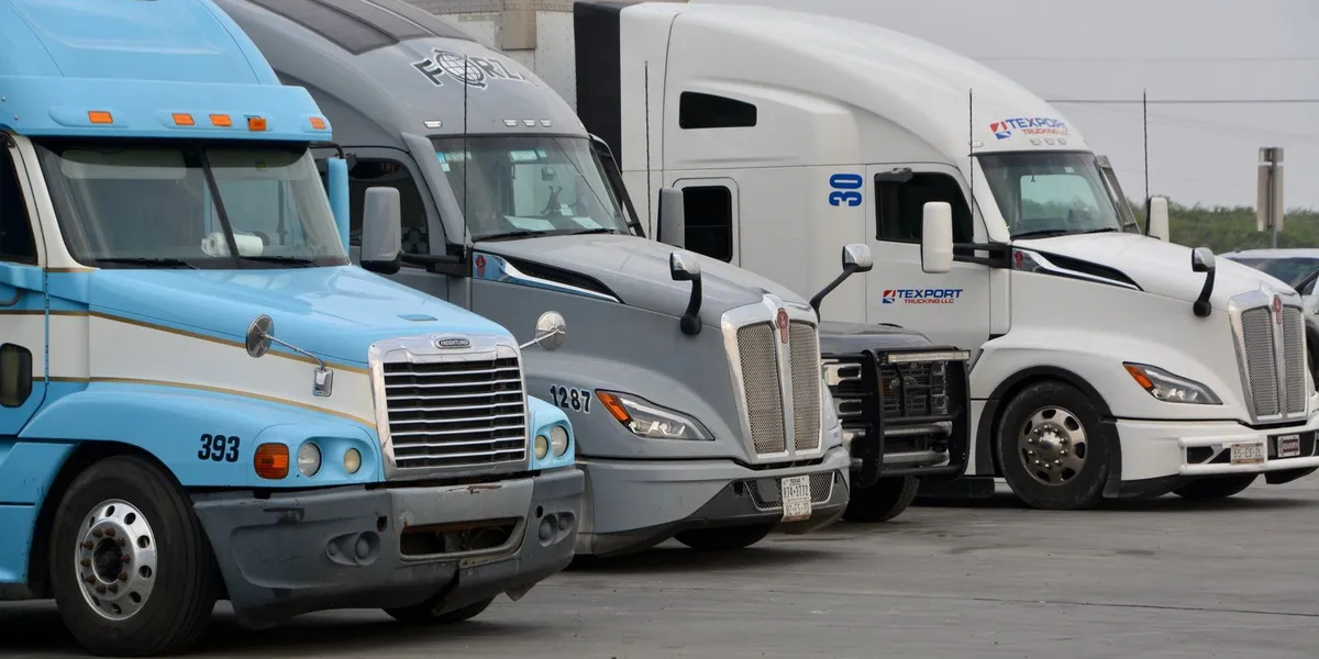 A row of parked semi trucks in Eagle Pass, Texas, showcasing various models and colors.