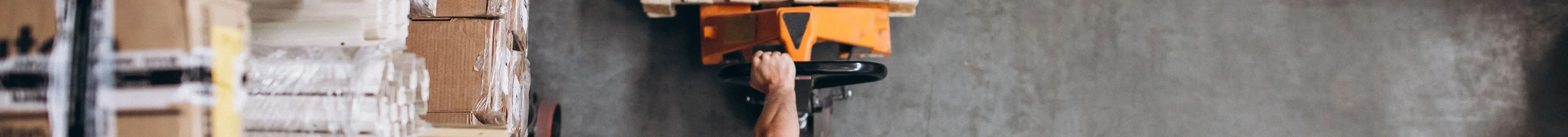 Worker with hard hat pulling a loaded pallet truck through a warehouse