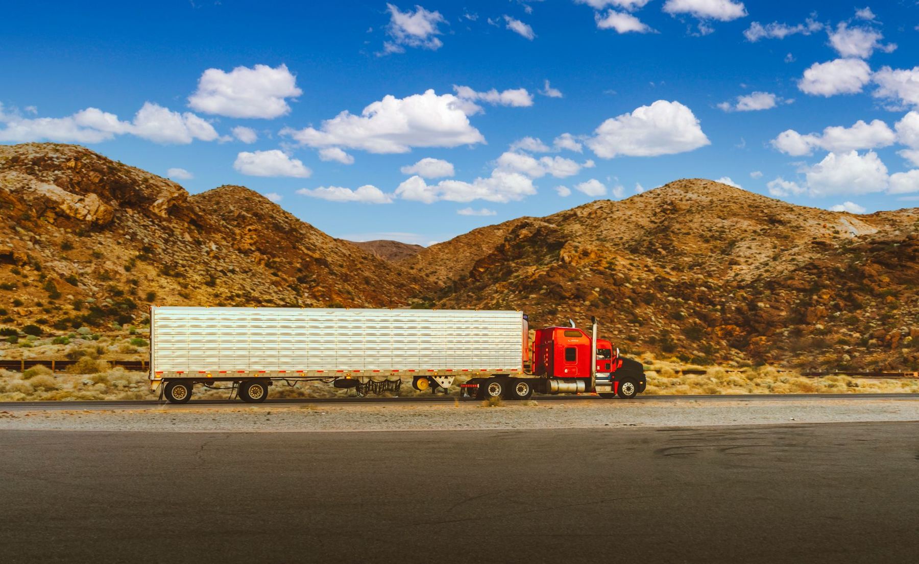 Red semi-truck with a flatbed trailer on a desert highway
